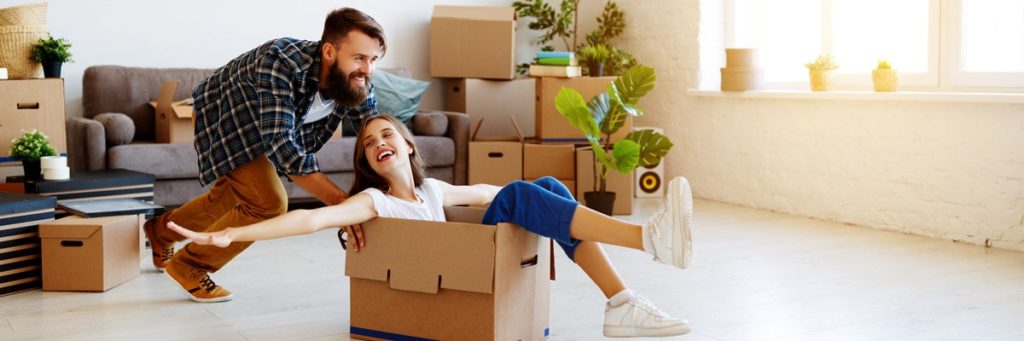Man pushing woman in moving box across the floor