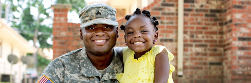 Soldier in uniform smiling with his daughter