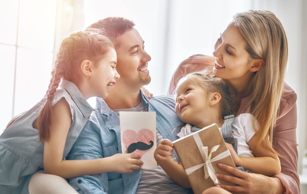 Family smiling on couch together with gift card and card