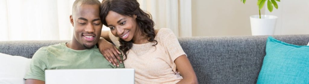 Couple sitting on couch looking at laptop together