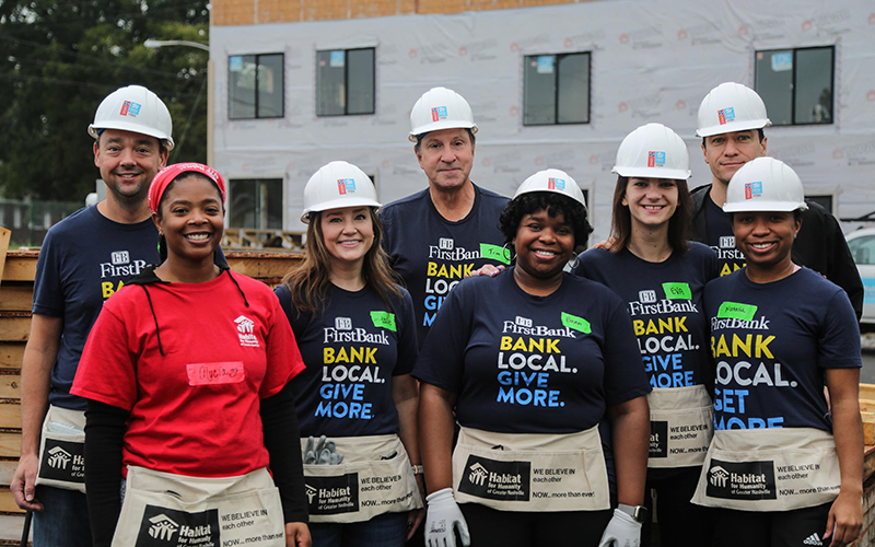 FirstBank volunteers wearing hardhats at construction site