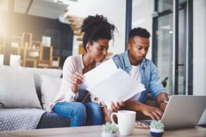 Couple filling out loan application on computer while sitting on couch